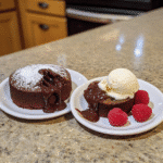 Chocolate lava cakes split open with molten chocolate center and vanilla ice cream.