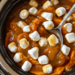 Slow cooker sweet potatoes topped with melted miniature marshmallows.