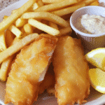 Fish and chips with crispy battered fish, fries, lemon wedges, and tartar sauce