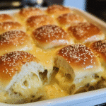 Close-up of baked cheese sliders with melted cheese and glossy tops in a baking dish