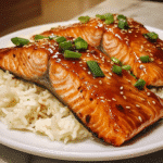 Glazed teriyaki salmon with sesame seeds and green onions next to rice
